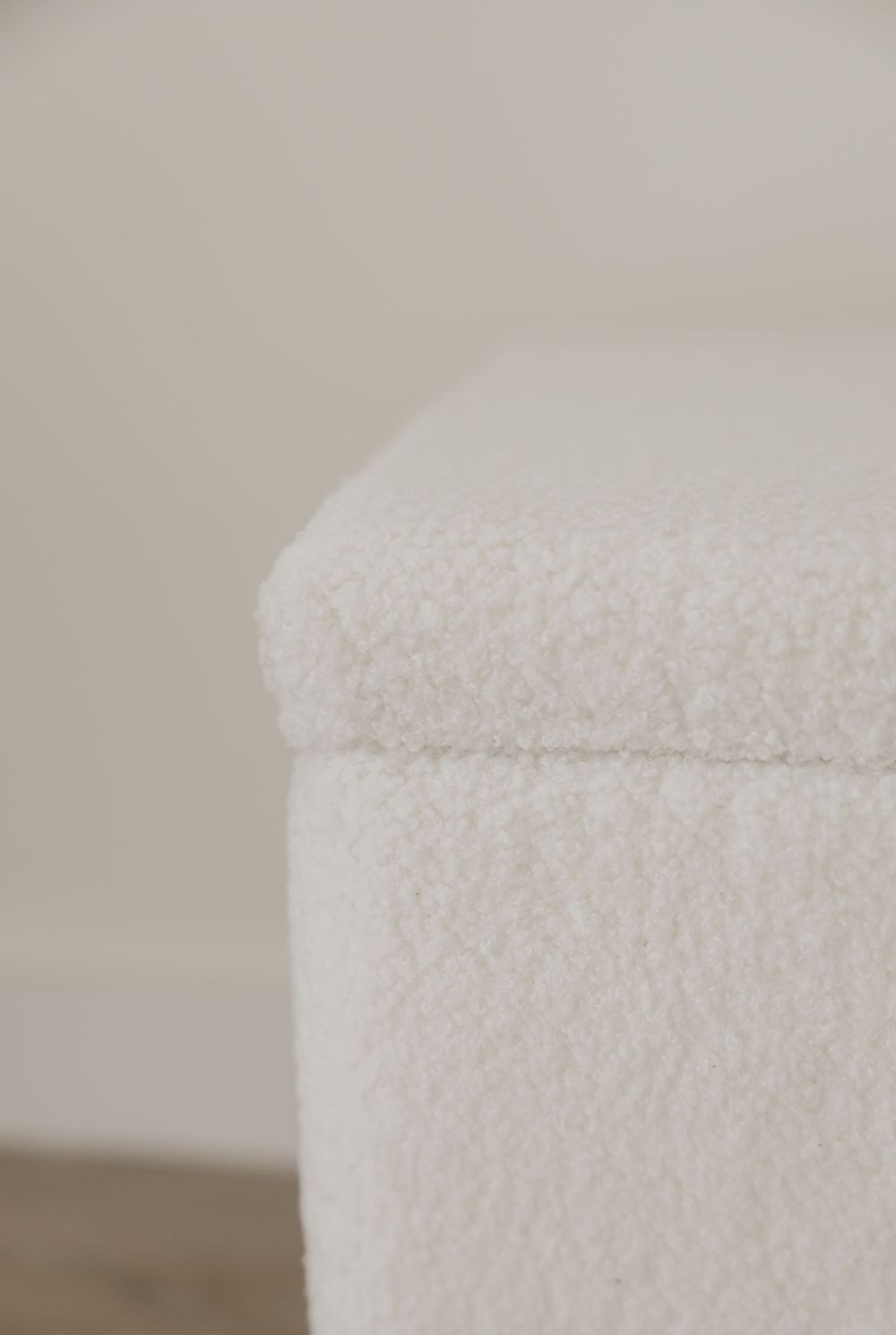 Close-up of neatly folded white fluffy towels creating soft minimalist texture against neutral background.