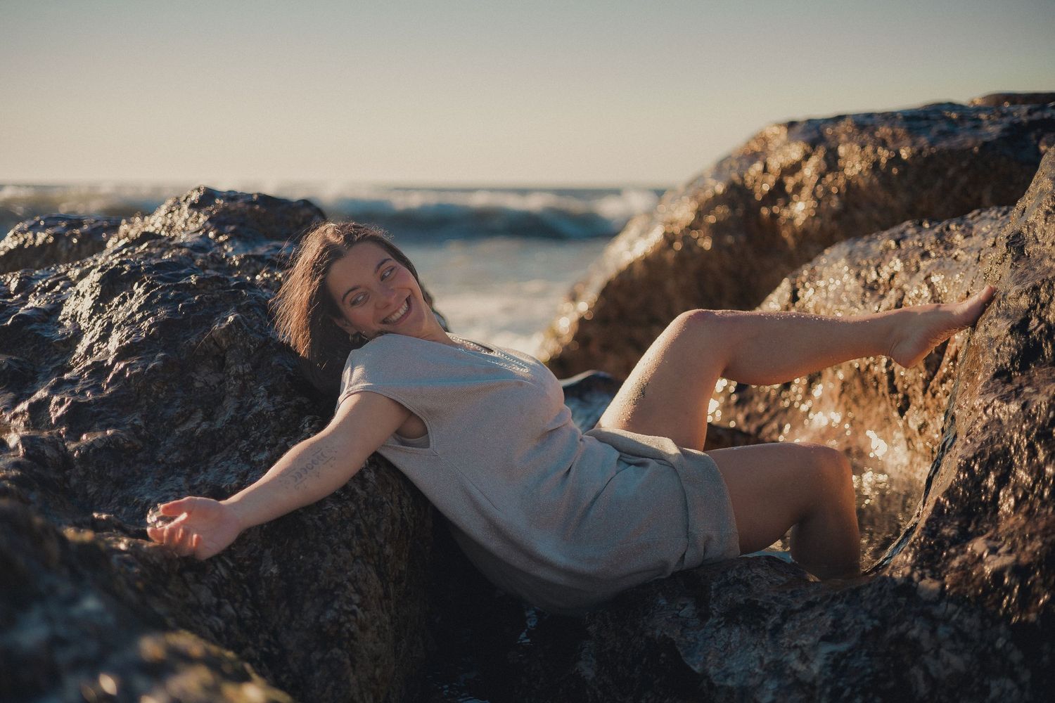 Dreamy golden hour portraits along rocky coastline with soft sunlight illumination.
