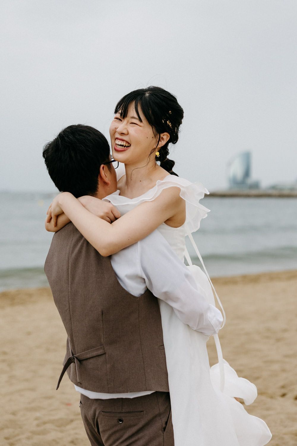 Joyful couple embracing and laughing during their beachside photoshoot.