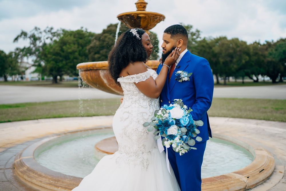 A couple dances lovingly by a water fountain during their wedding celebration outside.