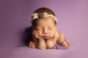 A series of peaceful newborn baby portraits against a soft purple backdrop showing different sleeping positions.