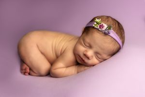 A series of artistic newborn baby photographs arranged horizontally showing peaceful sleeping poses on a pink background.