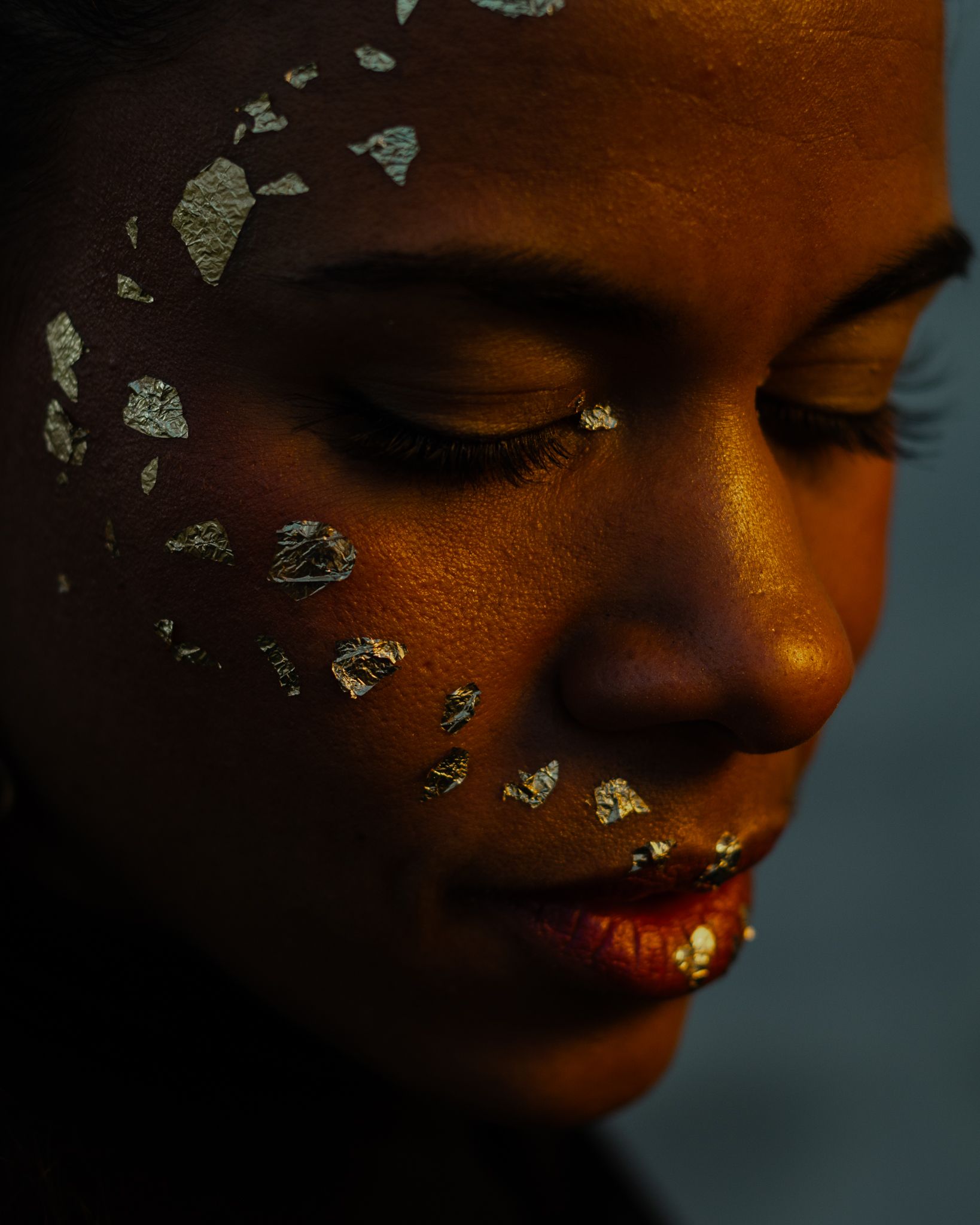 Close up portrait with metallic gold leaf decorative elements creating an artistic beauty shot.