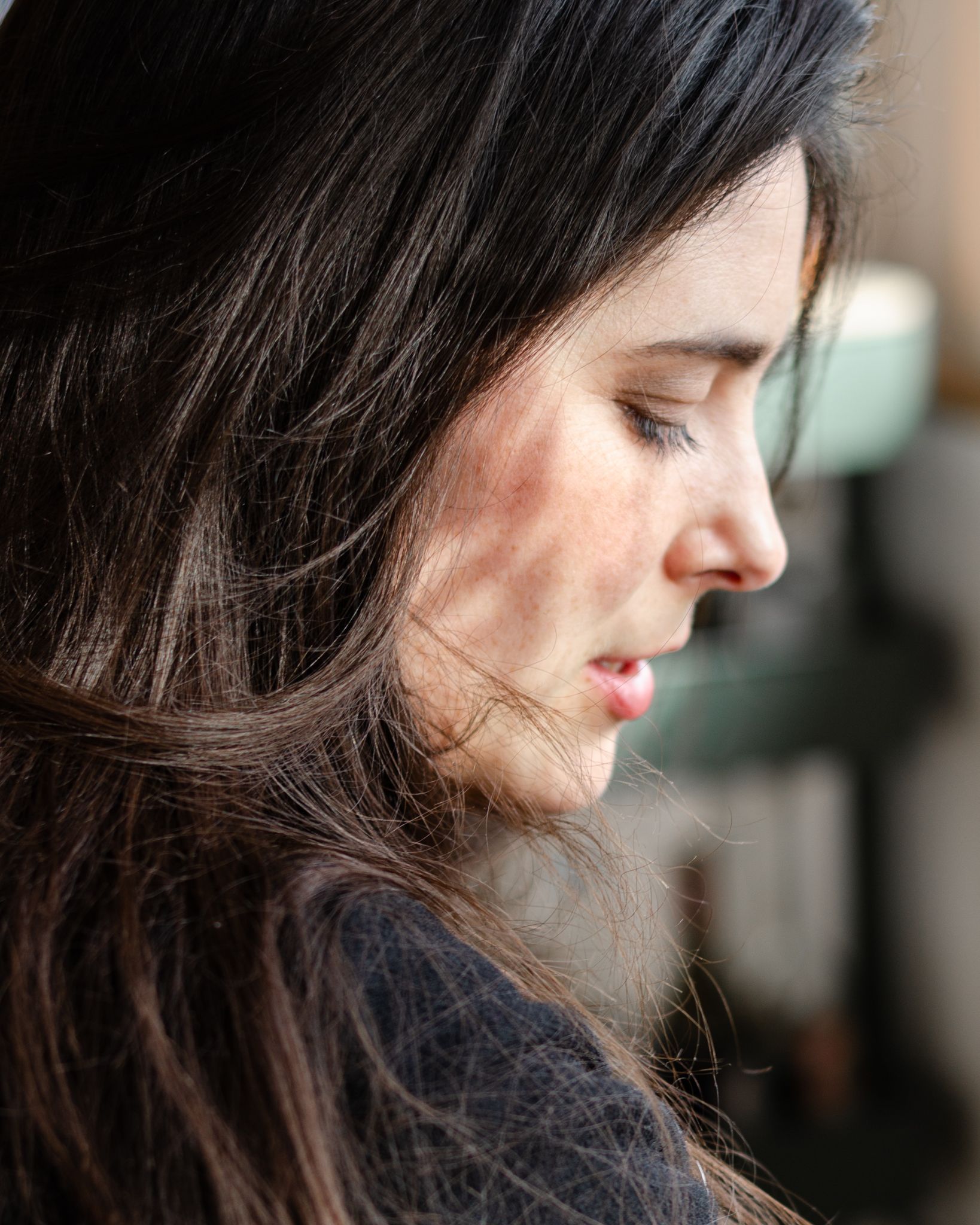 Side profile portrait with dark hair against soft lighting creating a dreamy atmosphere.