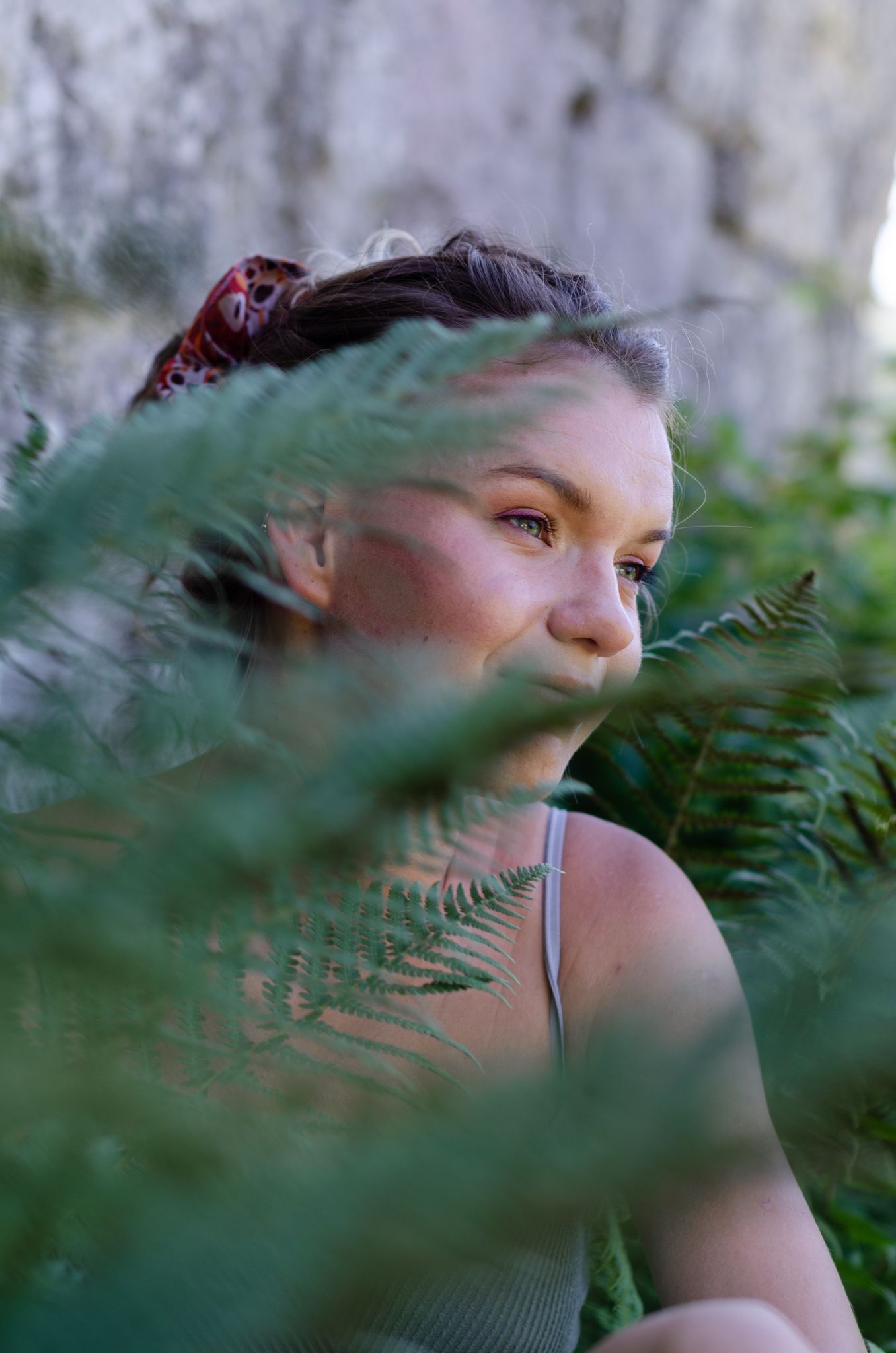 Artistic portrait through fern leaves creating a natural ethereal effect.