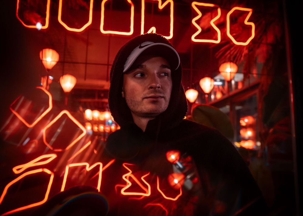 Red neon lights illuminate a dimly lit bar interior with glowing signage and warm ambient lighting.