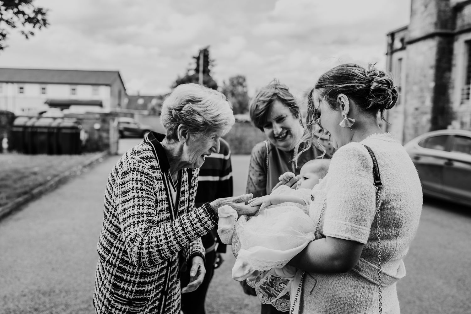 Three people gather together on a street having a joyful conversation in black and white photography.