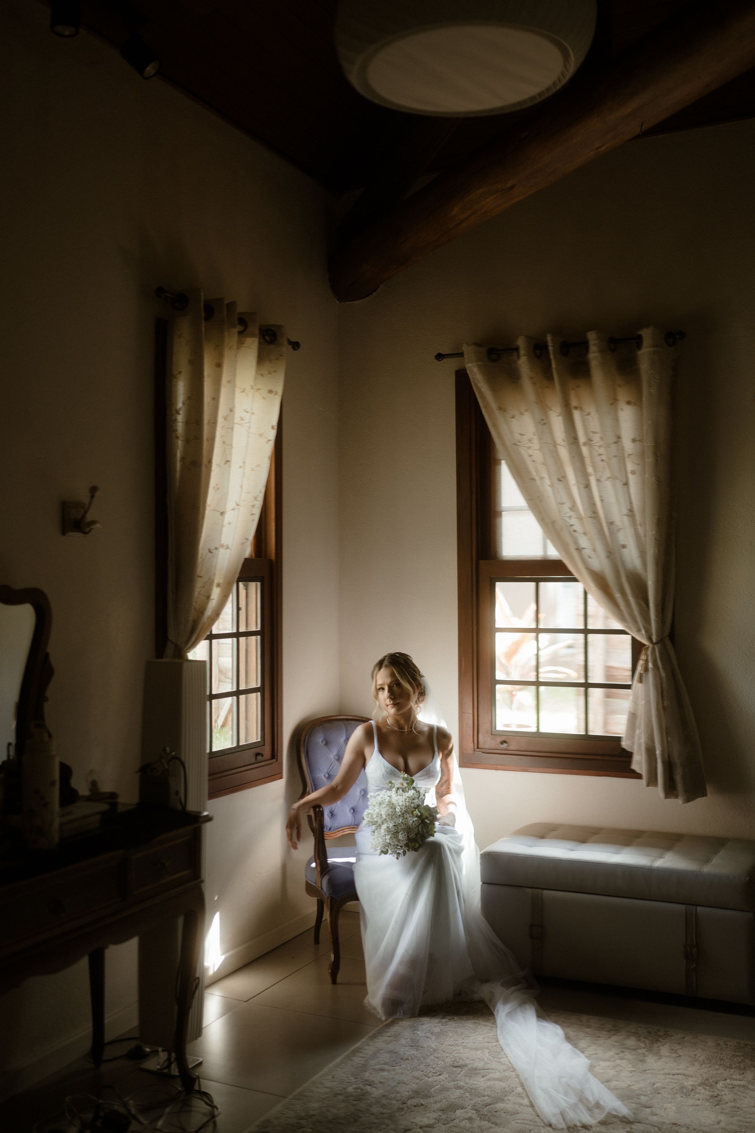 Ethereal silhouette in flowing white dress moves through sunlit room with vintage windows.