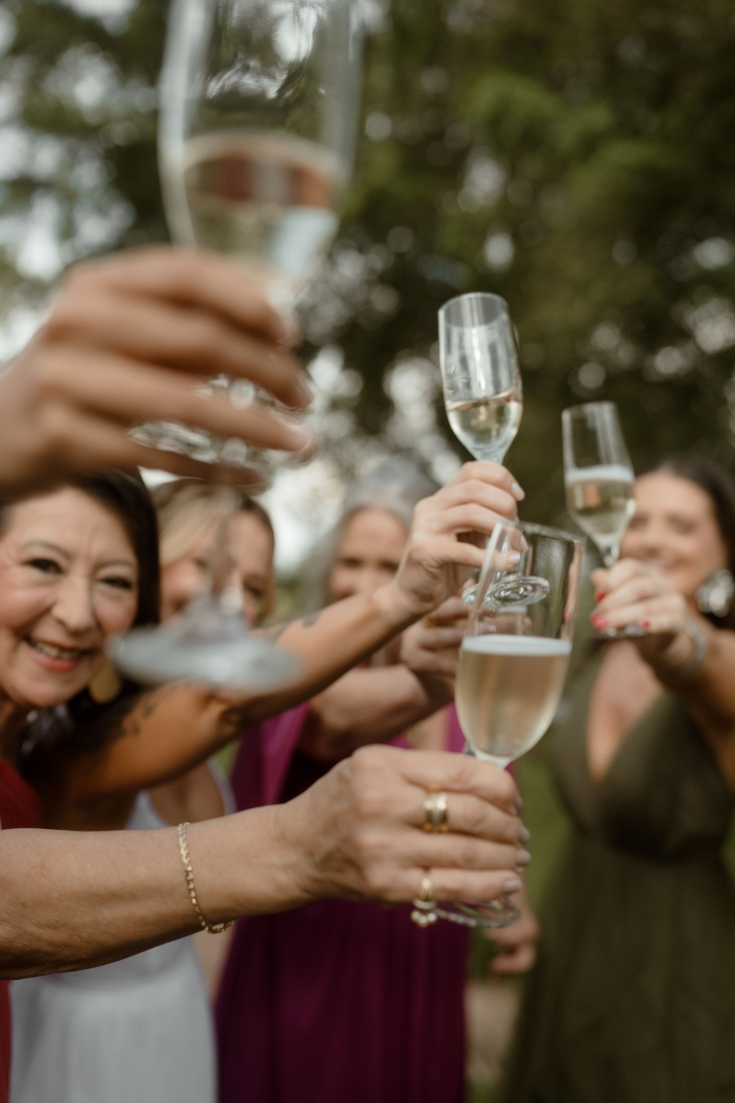 Champagne glasses clink together in celebration during outdoor wedding toast.