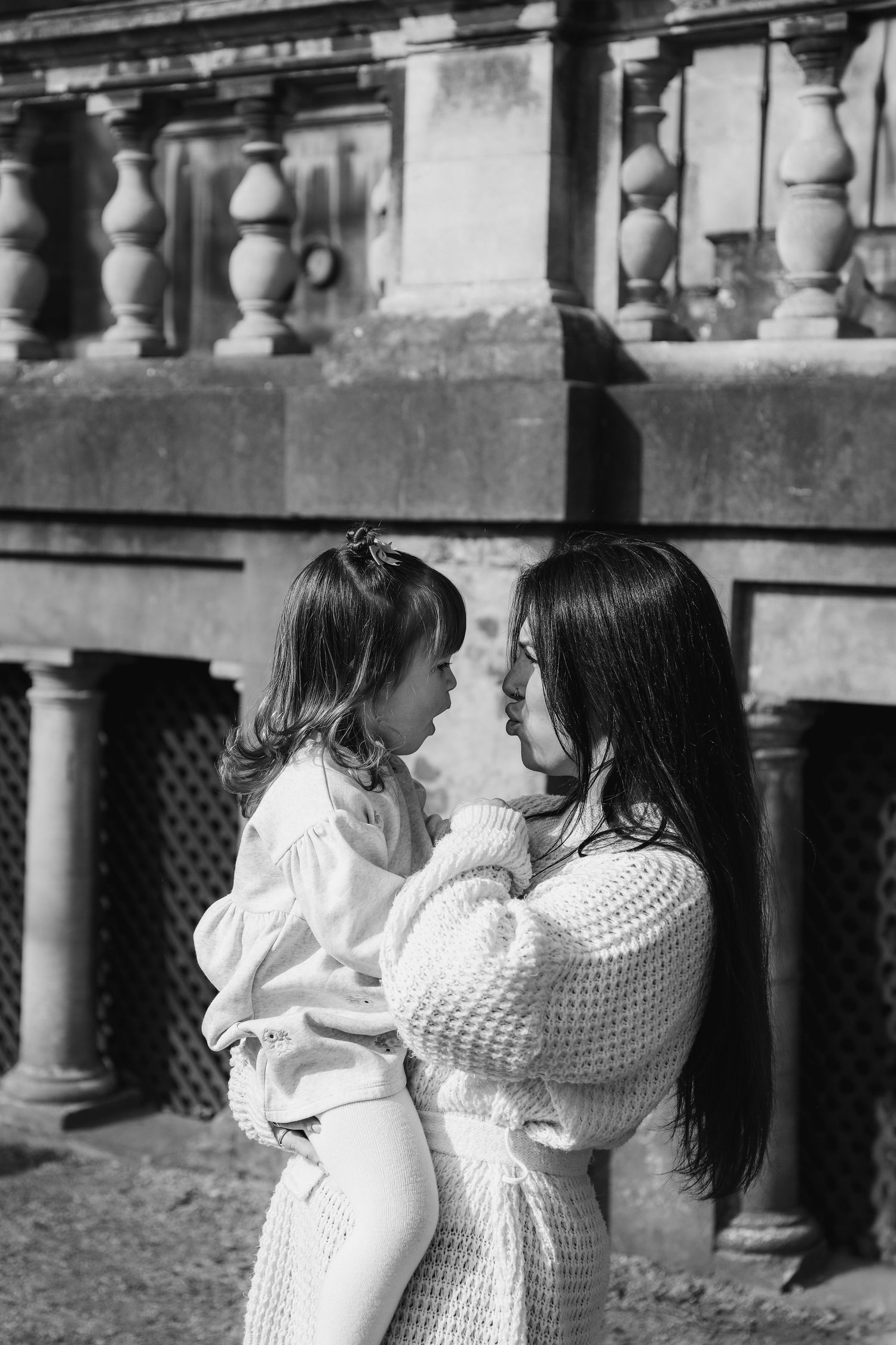 A touching black and white portrait of mum and daughter in matching white outfits sharing a tender moment outdoors, family shoot Nottingham