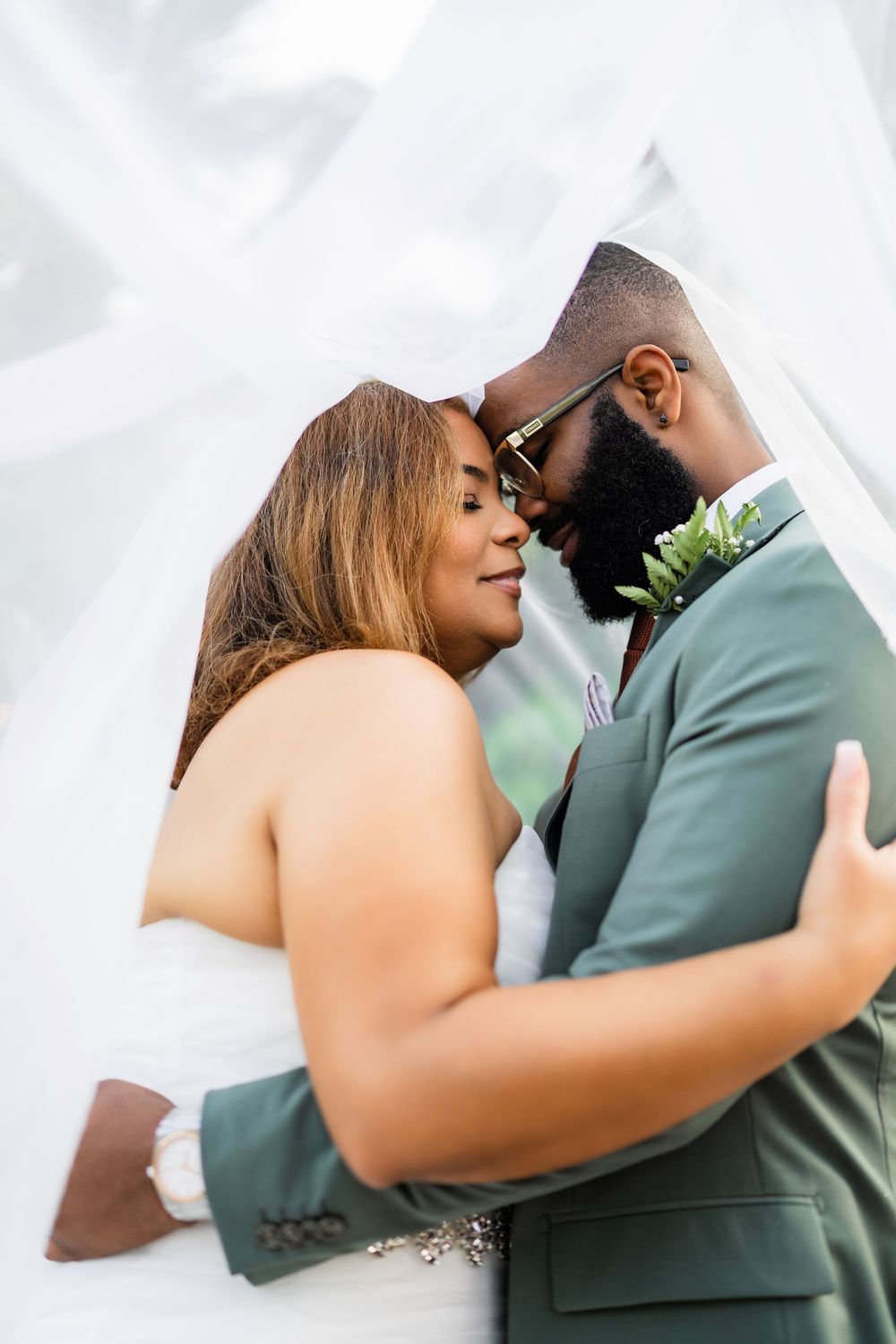 A romantic wedding moment as the newlyweds share an intimate embrace under flowing white fabric.