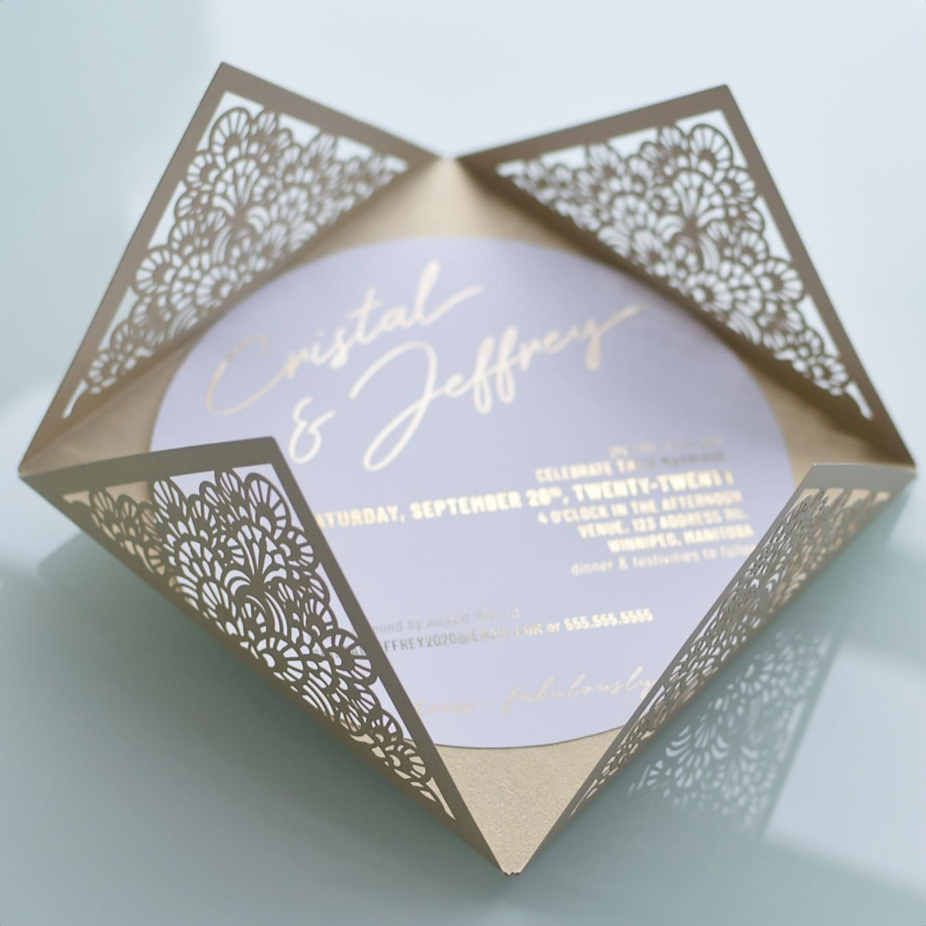Elegant gold laser-cut wedding invitation with intricate floral corner designs and gold text on a white linen paper.