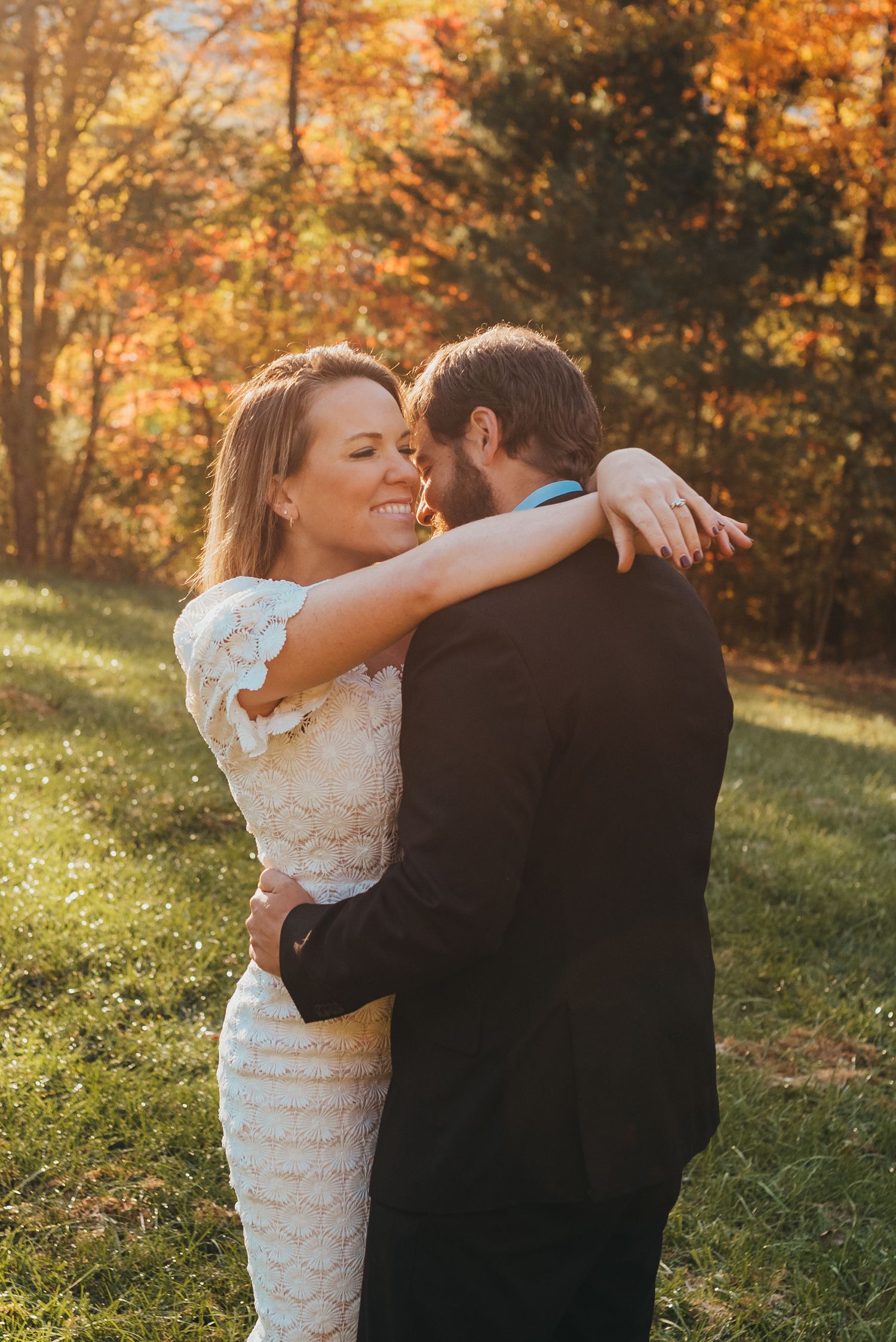 A couple embraces in an intimate dance pose against a backdrop of fall foliage.