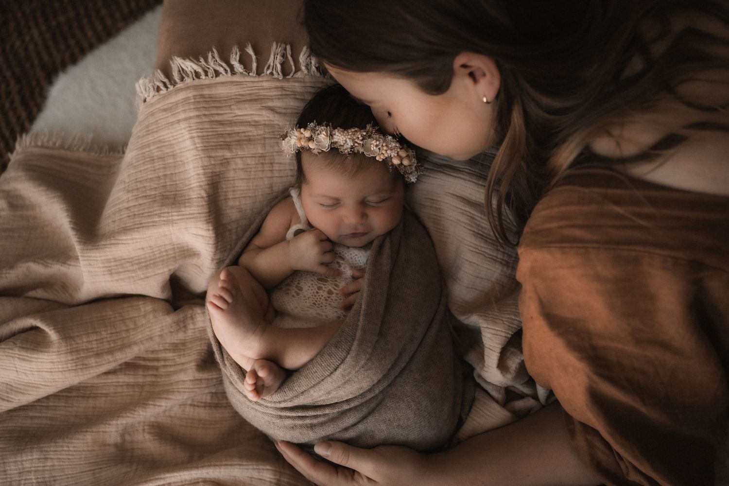 Parents in soft neutral clothing embrace their newborn baby while standing near window in intimate family moment.