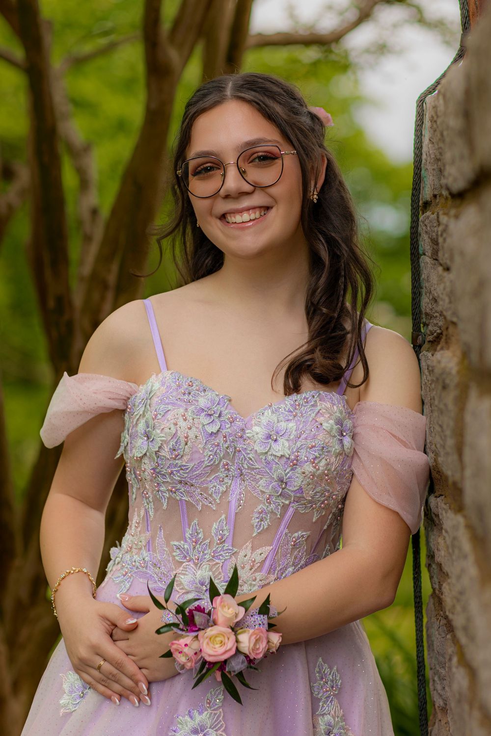 Springtime formal photo featuring a lavender gown and delicate pink corsage against garden backdrop.