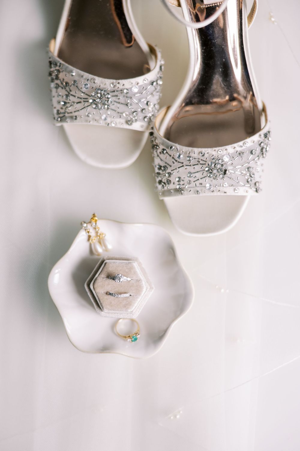 Elegant bridal shoes with crystal embellishments displayed next to a hexagonal jewelry dish with rings and accessories at Hall of Springs.