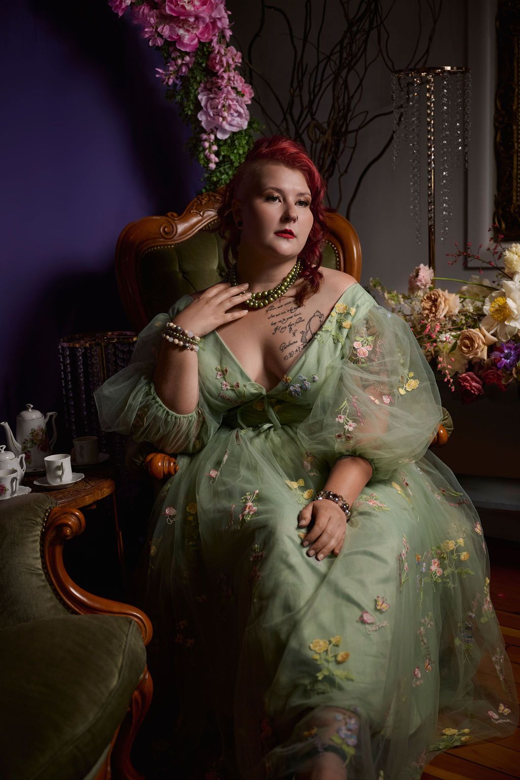 A glamorous vintage-style portrait showing someone in a mint green floral dress posing on an antique chair with decorative flowers.