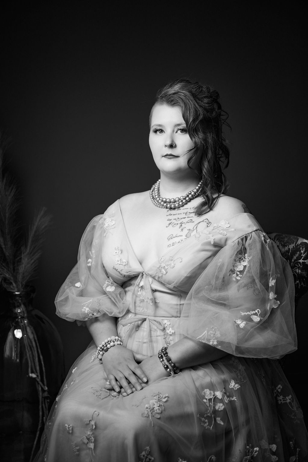 Black and white vintage style portrait in Victorian dress with pearls and lace details against dark background.