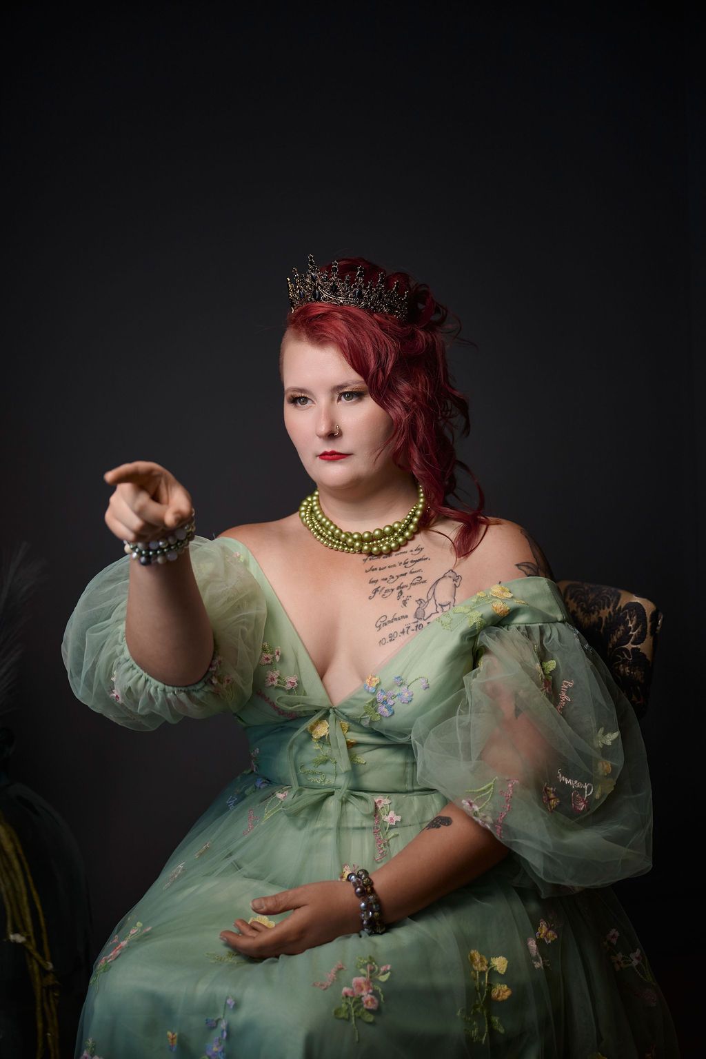 Renaissance style portrait in mint green gown with floral embroidery, crown, and gold necklace against dark background.