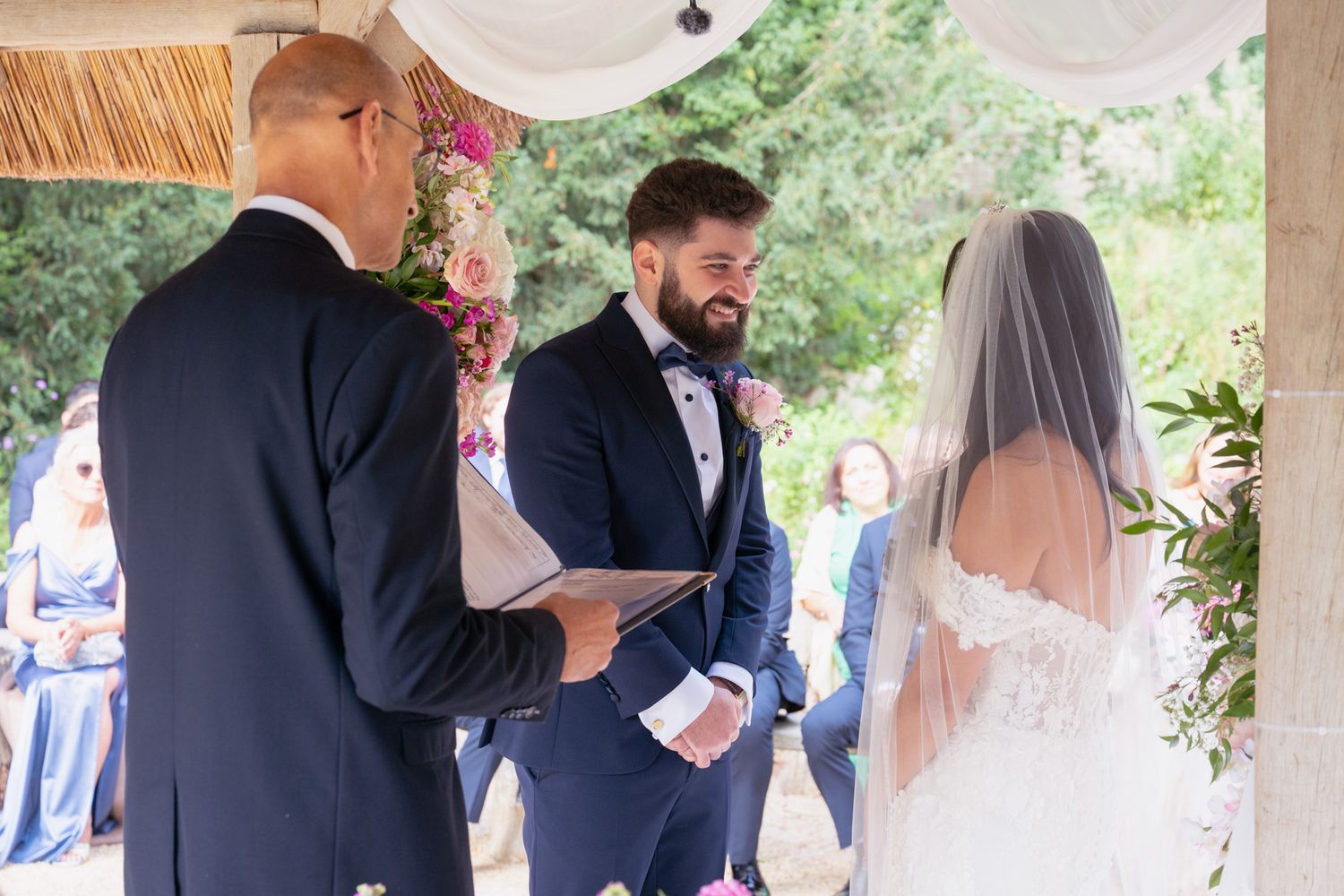 Wedding party members embrace and celebrate during an outdoor garden ceremony.