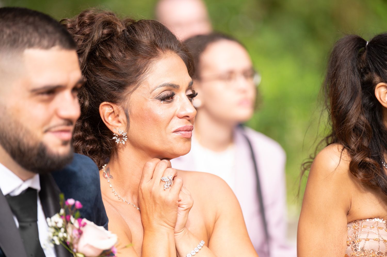 Wedding party poses together outdoors with lush greenery and floral arrangements in the background.