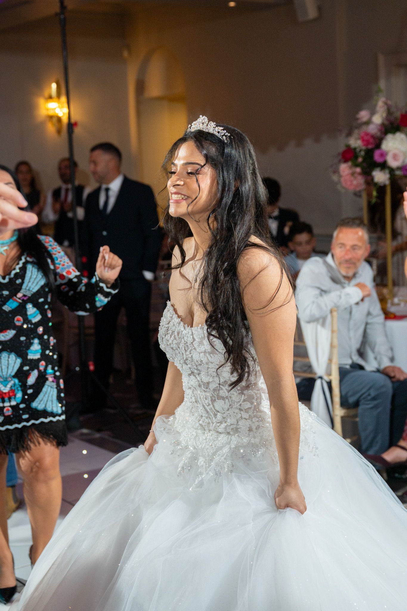 A bride in a flowing white ballgown twirls on a dance floor during a wedding reception.