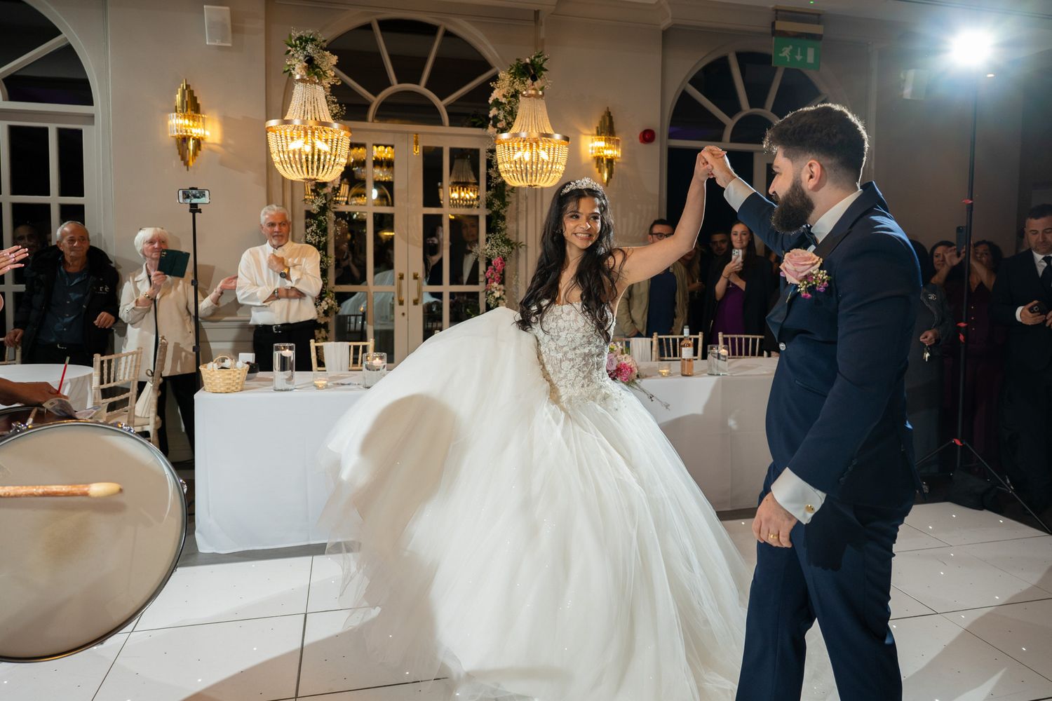 Newlyweds share their first dance under elegant crystal chandeliers in a grand ballroom reception venue.