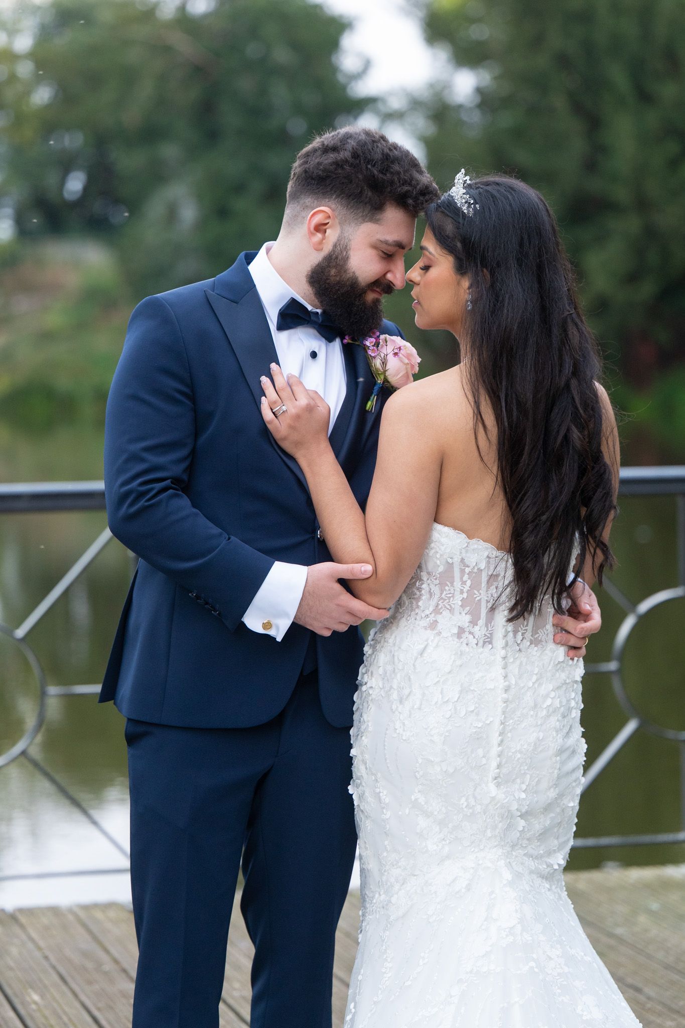 A romantic wedding couple shares intimate kisses on a wooden dock by a lake in a series of photos.