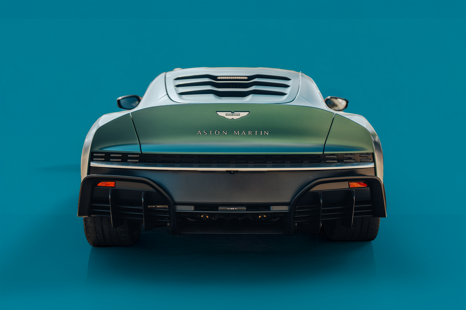 Rear view silhouettes of modern sports cars against a turquoise background.
