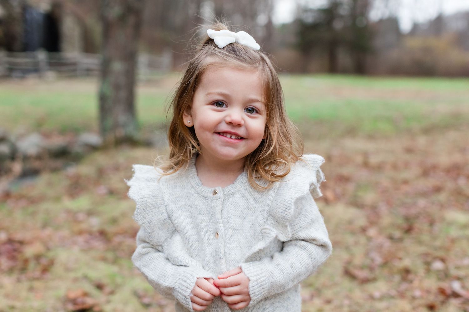 A series of outdoor autumn portraits showing a child in a white lace dress playing and smiling among fallen leaves.