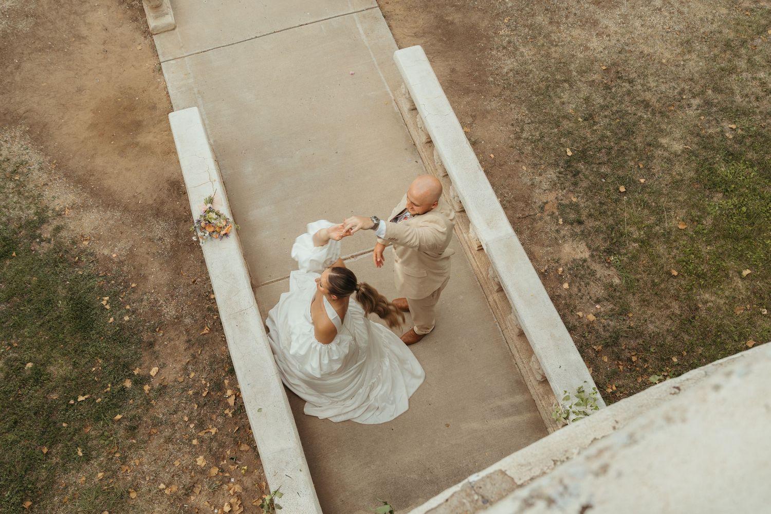 A man dressed in a suit spins his wife dressed in a wedding dress.