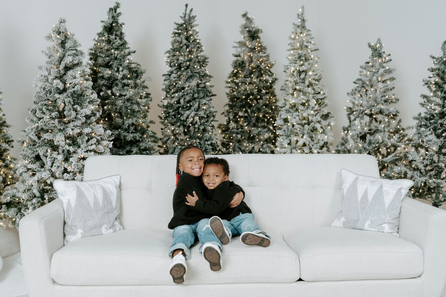 A person lounges comfortably on a white couch with snowy evergreen trees visible through large windows behind them.