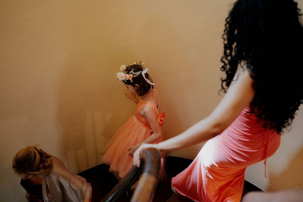 Two people in pink and orange dresses dancing together with dynamic movement against a neutral wall.