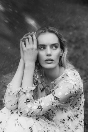 Artistic black and white portrait series featuring delicate floral pattern dress against dark background.