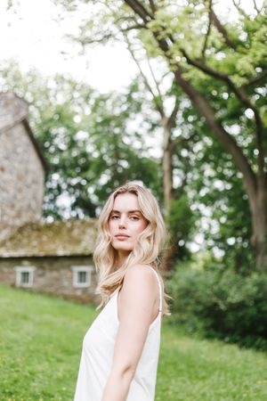 A light and airy summer portrait taken in a garden setting with natural greenery in the background.