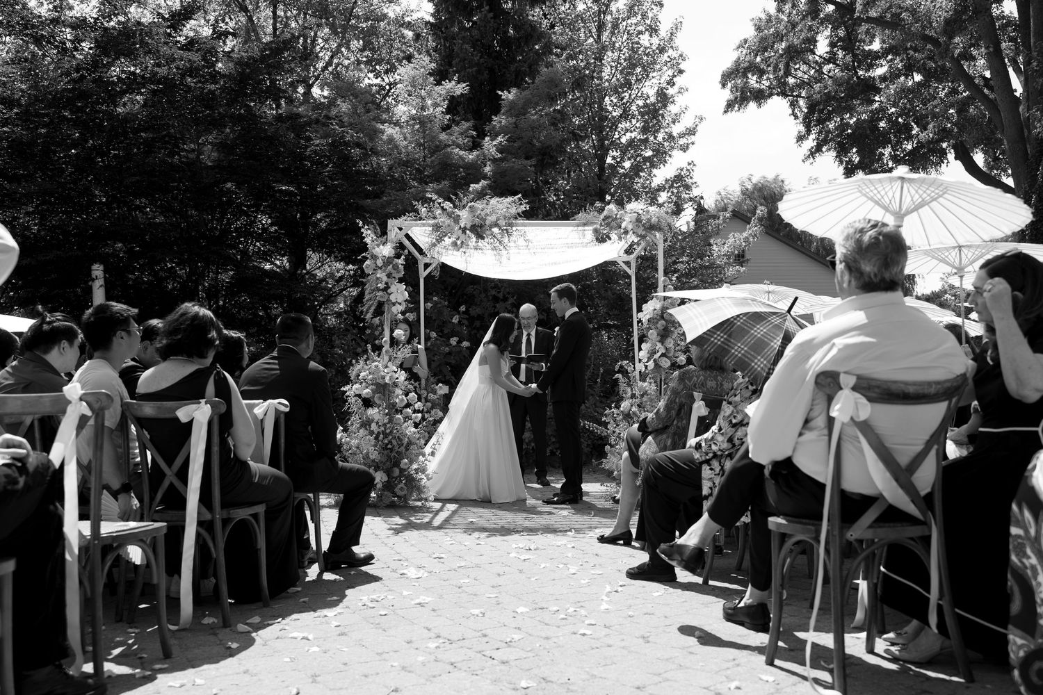 A black and white wedding photo of a couple standing in front of a grand historic mansion with classical architecture.