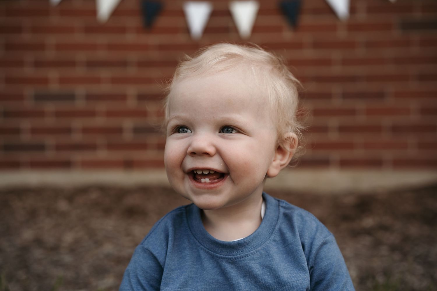 A series of candid portraits showing joyful expressions against a rustic brick wall background during lifestyle first year photo session