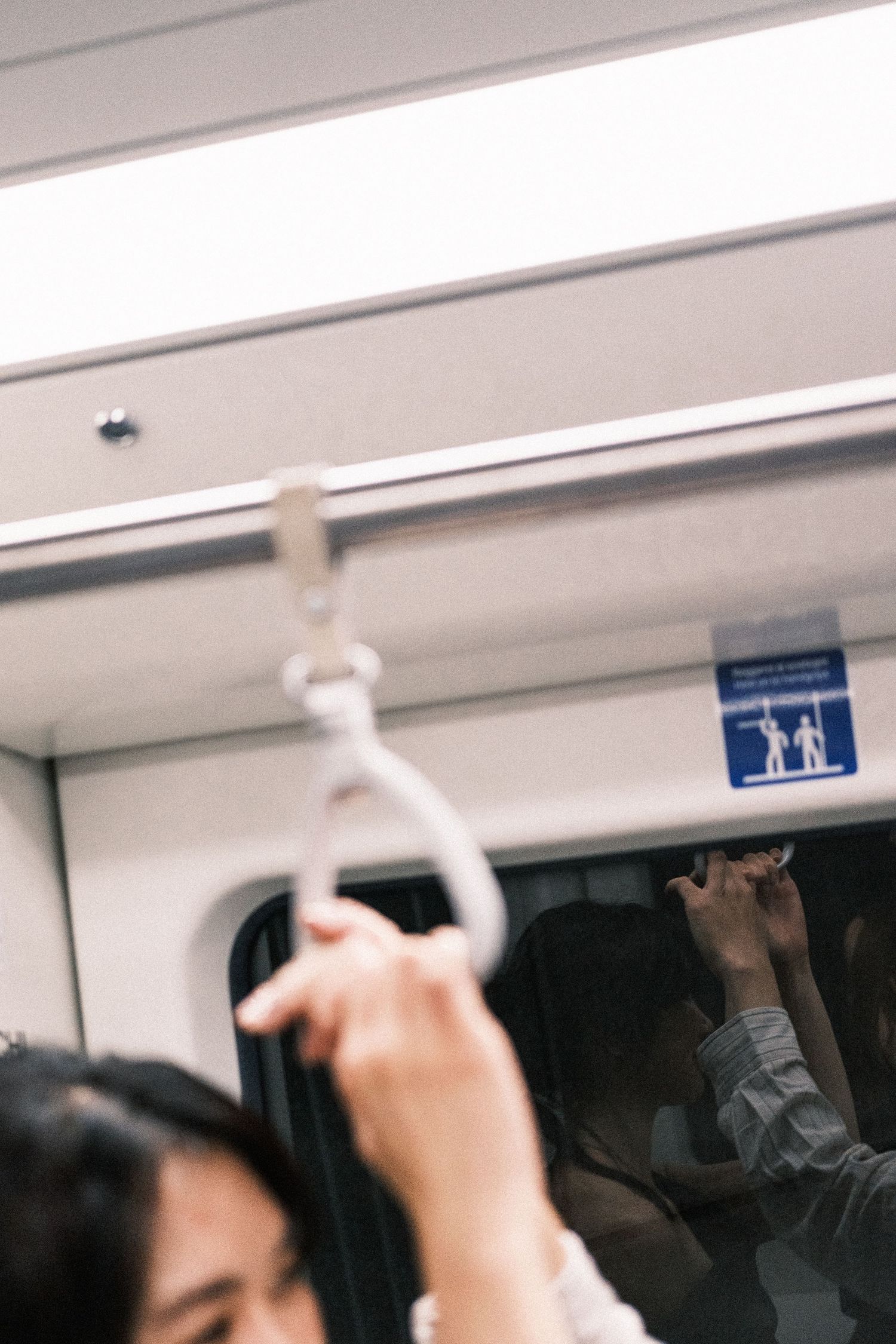 Commuters hold onto overhead handrails inside a moving subway train car.