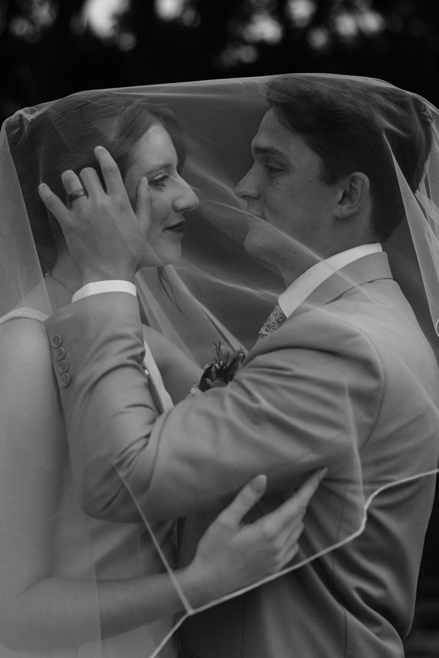A romantic wedding couple shares intimate moments under a weeping willow tree in a dreamy outdoor setting.