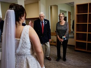 Wedding party gathered in a carpeted hallway with wood paneling and built-in shelving.