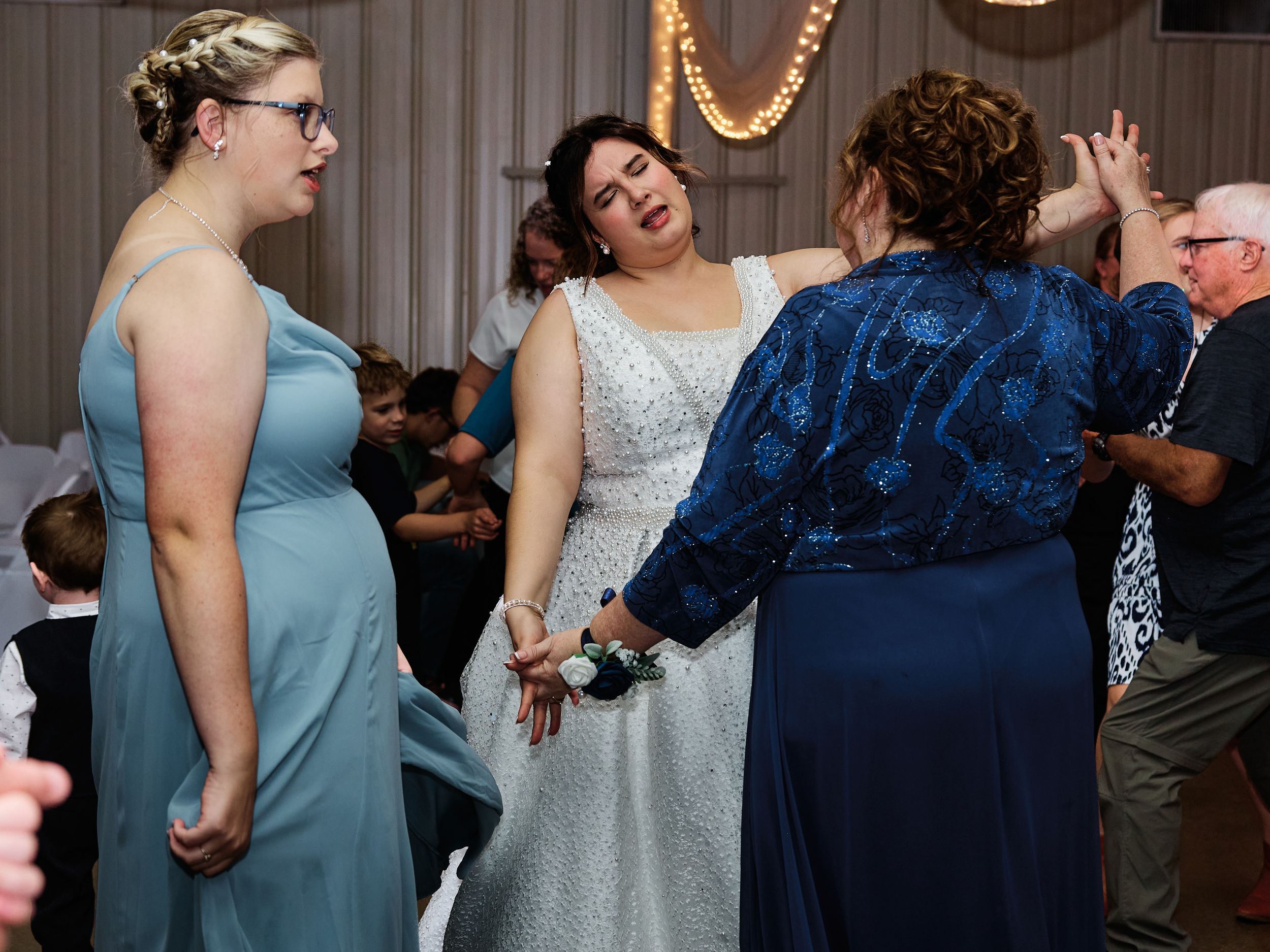 Wedding guests dancing and celebrating together on a dance floor at an indoor reception venue.