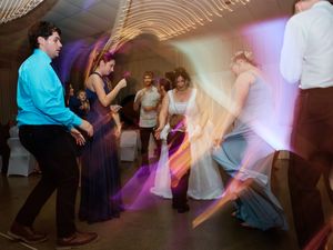 Motion-blurred dancers move energetically on a dimly lit dance floor with purple lighting effects.