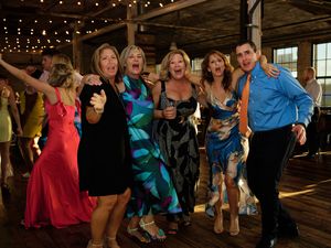 People dancing together in a rustic barn venue decorated with string lights during a social dance event.