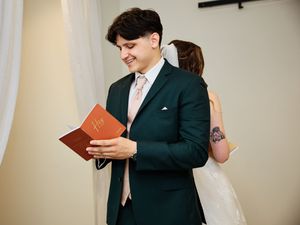 Professional in dark suit reading from a book during formal ceremony.