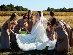 Wedding party poses together in a grassy field during golden hour.