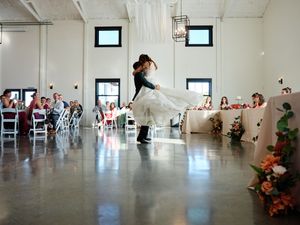 Modern white indoor event space with high ceilings and scattered seating arrangements.