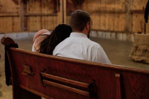 A row of wooden church pews in a dimly lit sanctuary with warm lighting and traditional architecture.