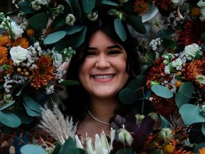Wedding party poses with eucalyptus greenery, burgundy florals and pampas grass in an elegant outdoor setting.