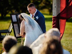 A couple shares an intimate moment during their outdoor wedding ceremony as guests look on from their seats.