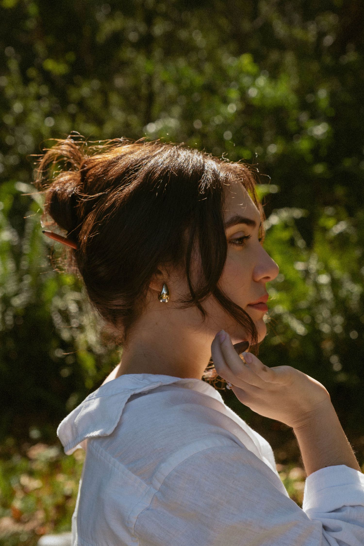 Artistic portrait sequence showing movement and emotion in white shirt against foliage.